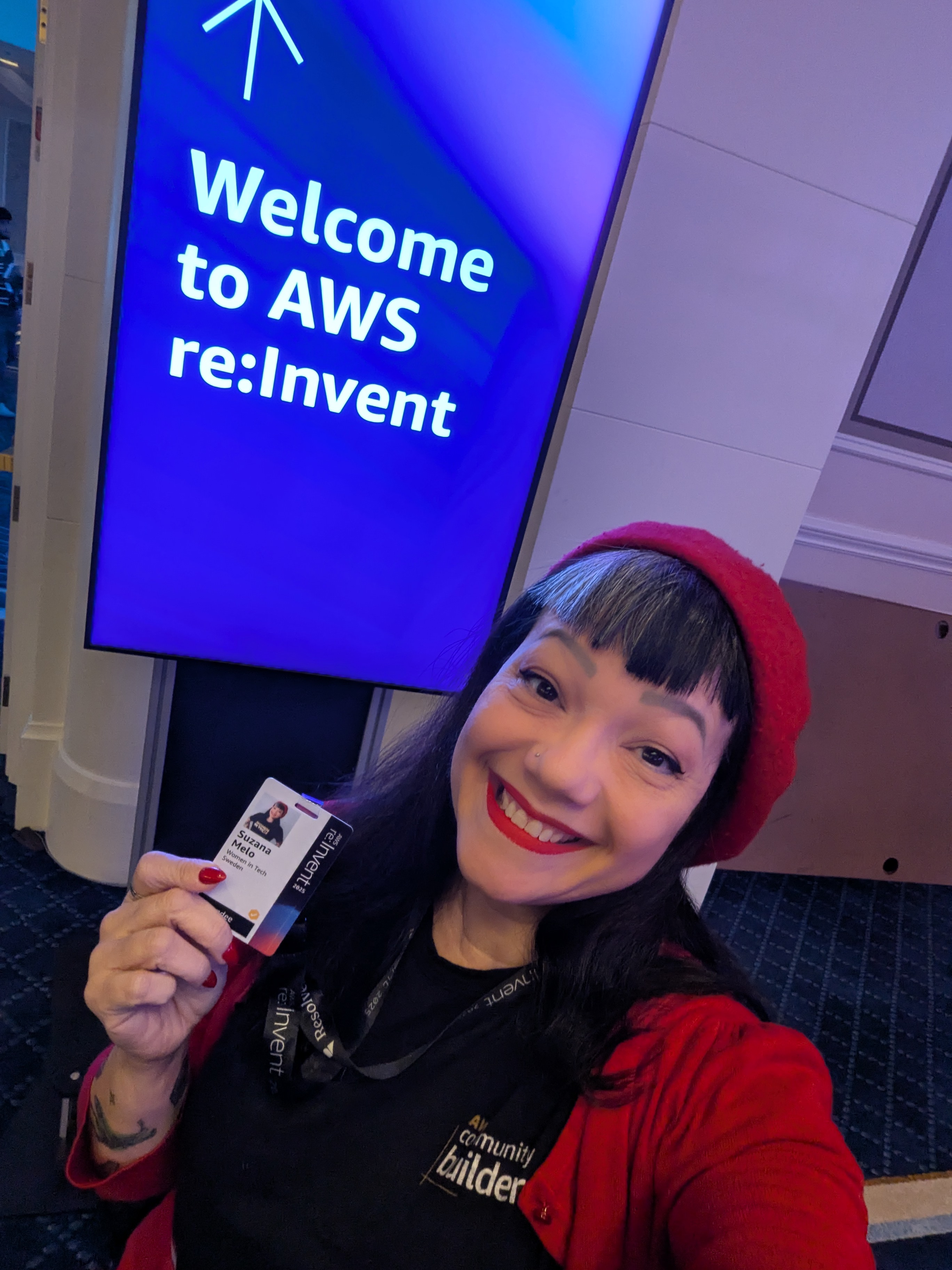 Suzana at AWS re:Invent 2025 holding her event badge